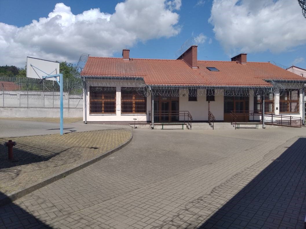 parterowy budynek zakładów karnych, przy boisku do koszykówki