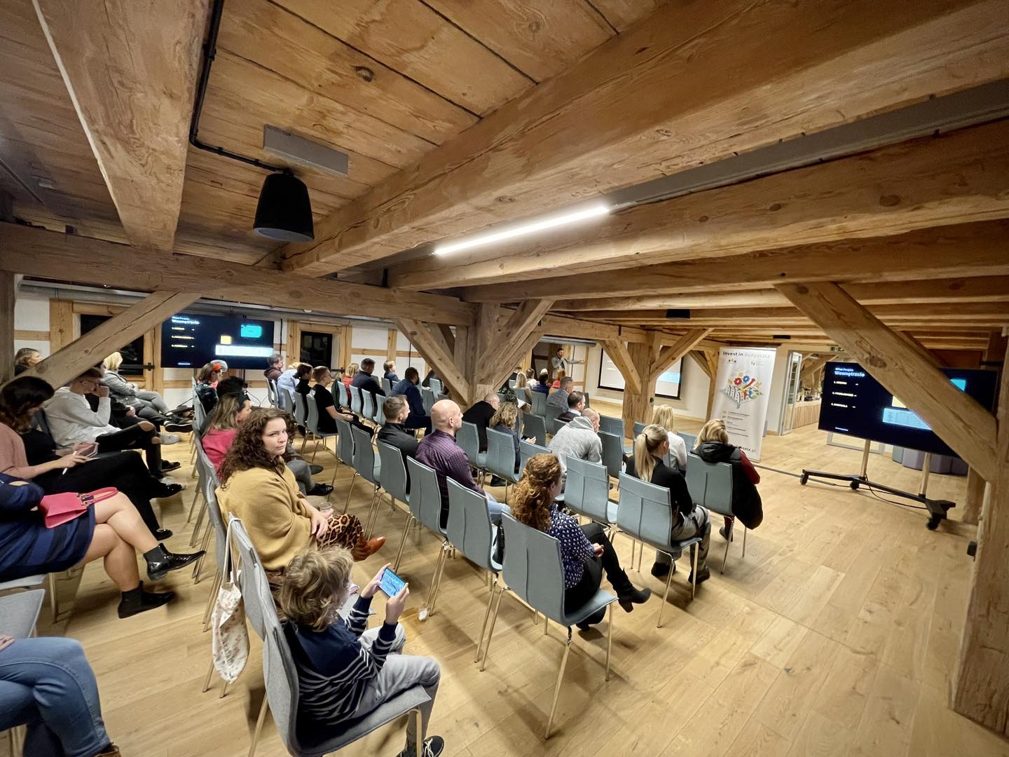 widok uczestników na tle sali, podczas wystąpienia jednego z prelegentów