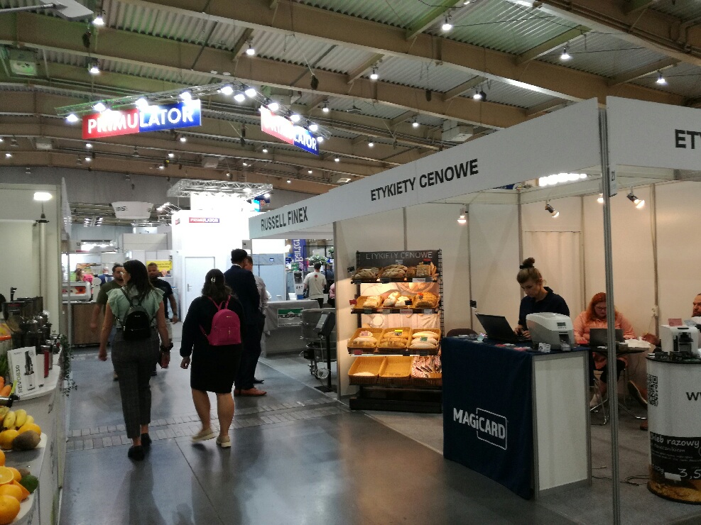 kilka stoisk wystawowych i spacerujący goście