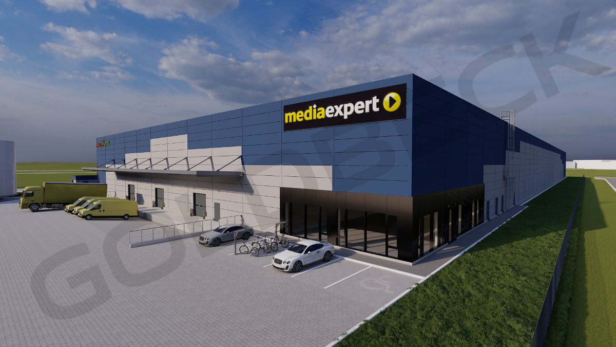 szaro-niebieski budynek z zółto-białym napisem Mediaexpert. w częście załadunkowej stoją dostawcze samochody, część wejściowa do bydynku jest cała przeszkłona, przed pudynkiem są miejsca parkinkowe oraz stelaż do pozostawienia rowerów